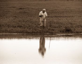 Reflection of senior man fishing on lake