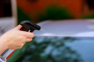 Close-up of person using spray bottle on car