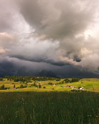 Dramatic wide angle shot of a mountain madow at sunset with dark storm clouds