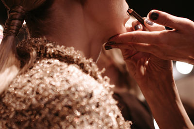 Fashion shot of makeup artist doing brown lips with a brush, make up visage process