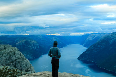 Rear view of man standing on mountain against sky