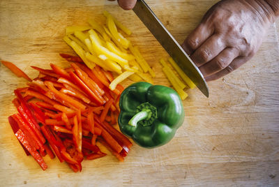 Cropped hand of person cutting vegetables on table