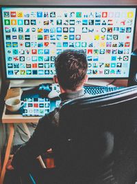 Rear view of man using computer while sitting on chair at office