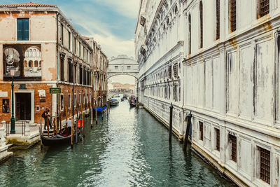 Boats in canal amidst buildings against sky