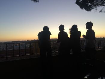 Silhouette men standing against sky during sunset