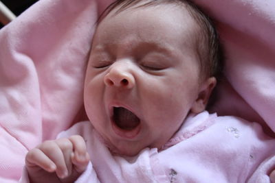 Close-up of cute baby girl yawning in crib