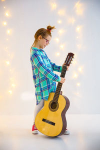 Young woman holding guitar against sky