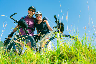 Portrait of smiling young woman with bicycle on field