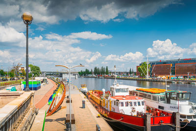 Panoramic view of harbor by city against sky