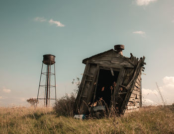 Old damaged building on field against sky