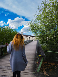 Woman standing by railing against sky