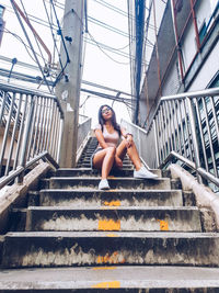 Low angle portrait of woman sitting on staircase