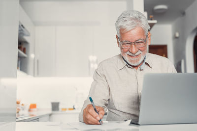 Portrait of senior man using laptop at home