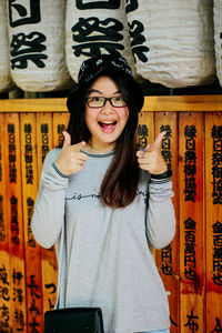 Portrait of happy young woman gesturing while standing against wall