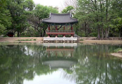 Gazebo by lake against trees and plants