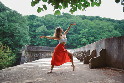 Rear view of woman with arms raised against trees