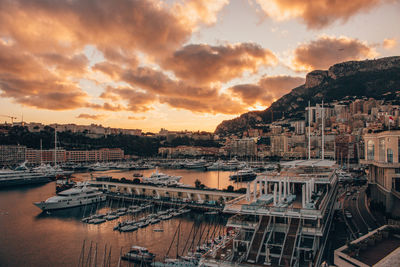 Sailboats moored in harbor against sky during sunset