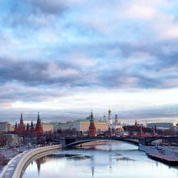 Arch bridge over river in city against sky