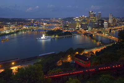 High angle view of illuminated city by river against sky