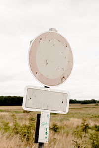 Damaged road sign on field against clear sky