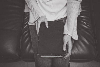 Midsection of woman with book on seat 