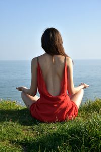 Rear view of woman doing yoga at beach