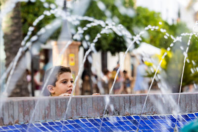 Portrait of a little kid surrounded by water jets