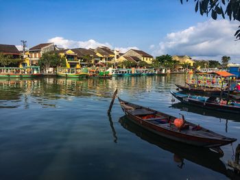 Boats moored on lake by buildings against sky