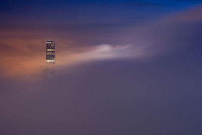 Light trails on building against sky at dusk