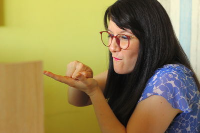 Portrait of young woman holding eyeglasses at home