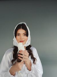 Portrait of young woman wearing mask against white background