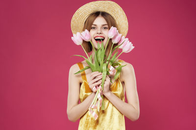 Portrait of woman wearing hat against pink background