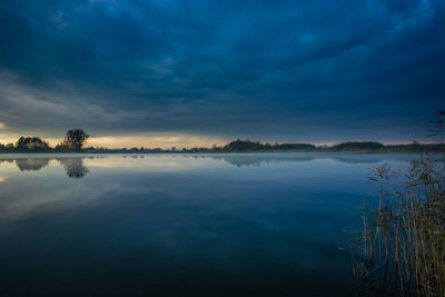 Dark blue clouds over the lake with fog and reeds, eastern poland