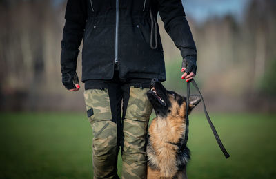 Midsection of man with dog standing outdoors