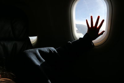 Cropped silhouette hand on airplane window