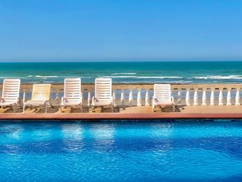 Swimming pool by sea against clear blue sky