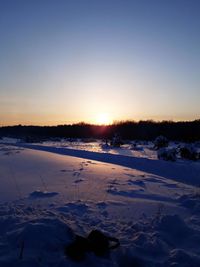 Scenic view of snow covered field against sky during sunset