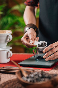 Midsection of woman measuring coffee beans in cafe