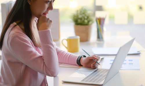 Midsection of woman using mobile phone while sitting on table