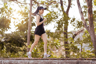 Side view of young woman against trees