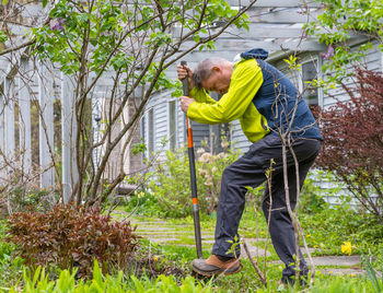 Side view of man with umbrella standing against plants