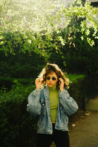 Young woman standing against plants