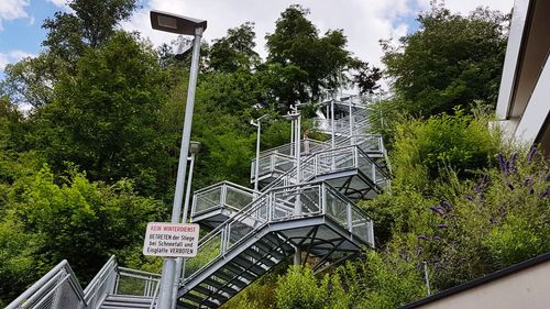 Low angle view of railroad tracks by trees against sky