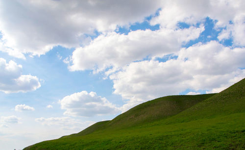 Low angle view of green hill against sky