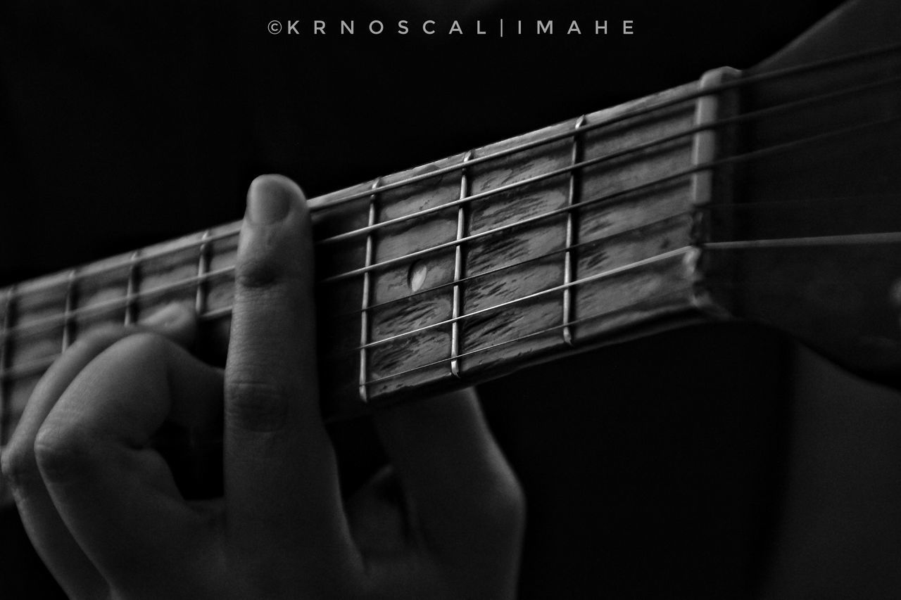 CLOSE-UP OF HAND PLAYING GUITAR IN BLACK