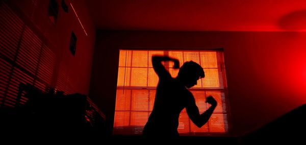 Silhouette woman standing against wall at home