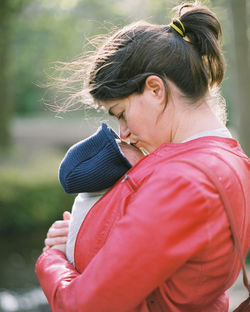 Side view of woman carrying baby boy while standing outdoors