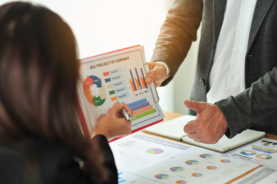 Midsection of business people working over graph on table at office