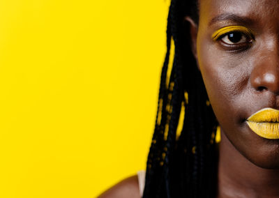 Portrait of young woman against yellow background