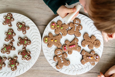 Directly above shot of boy decorating cookies in plate